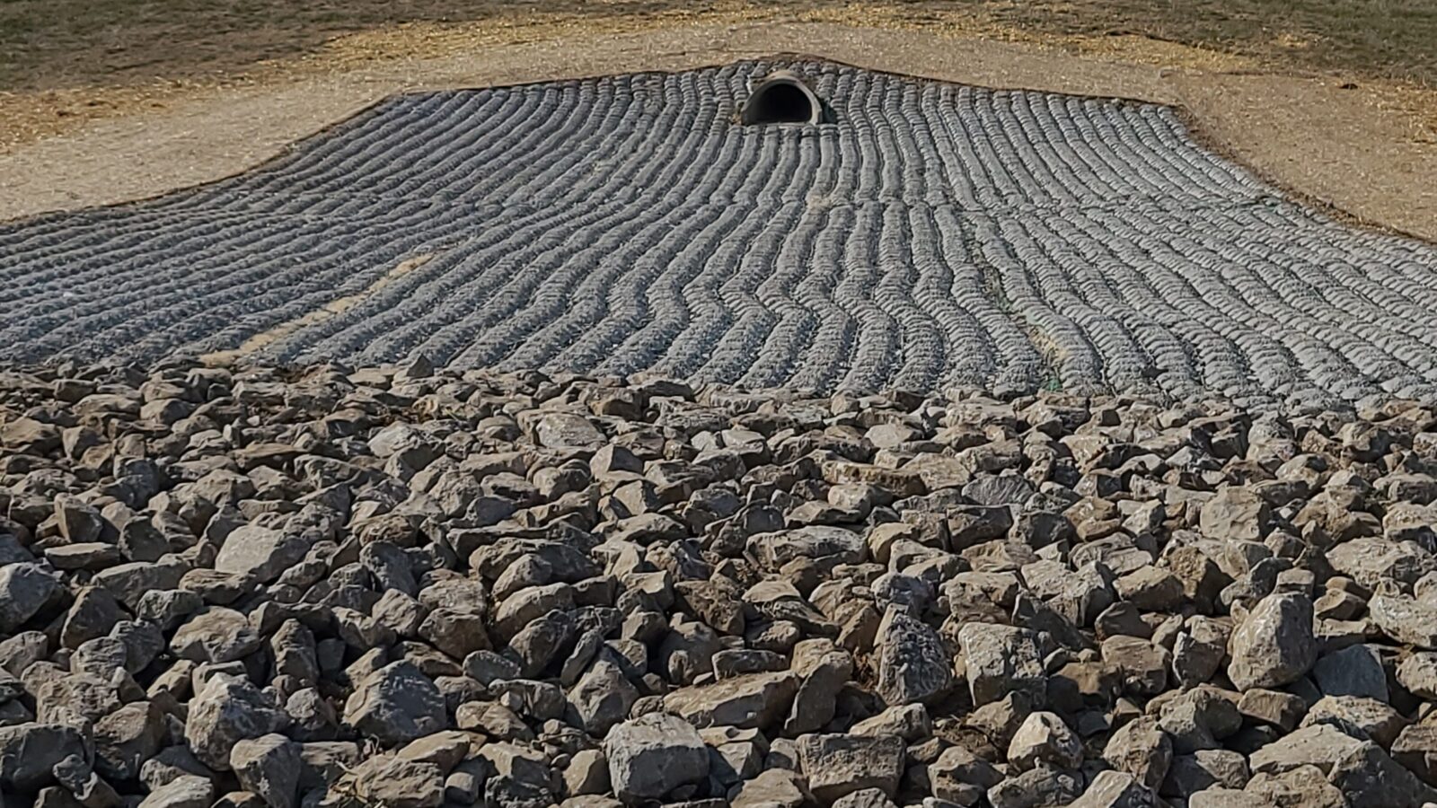 A cobblestone spillway constructed by Ladd Scape with rocks at the bottom