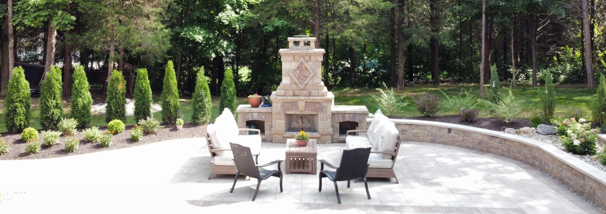 Completed stone patio and landscape featuring an outdoor fireplace